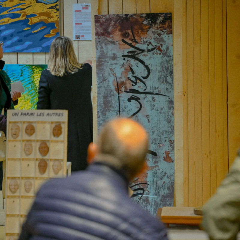 Visiteurs observant des toiles dans une exposition artistique